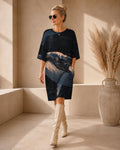 May include: A knee-length, short-sleeved dress in dark navy blue featuring a prominent abstract graphic print of a whale in shades of cream, light blue, and dark blue. The garment has a round neckline and a relaxed, straight-cut silhouette.