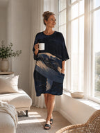 May include: A knee-length, short-sleeved dress in a dark navy blue hue, featuring a prominent abstract graphic print of swirling waves in shades of cream, light blue, and deep indigo. The garment includes a round neckline and side pockets.