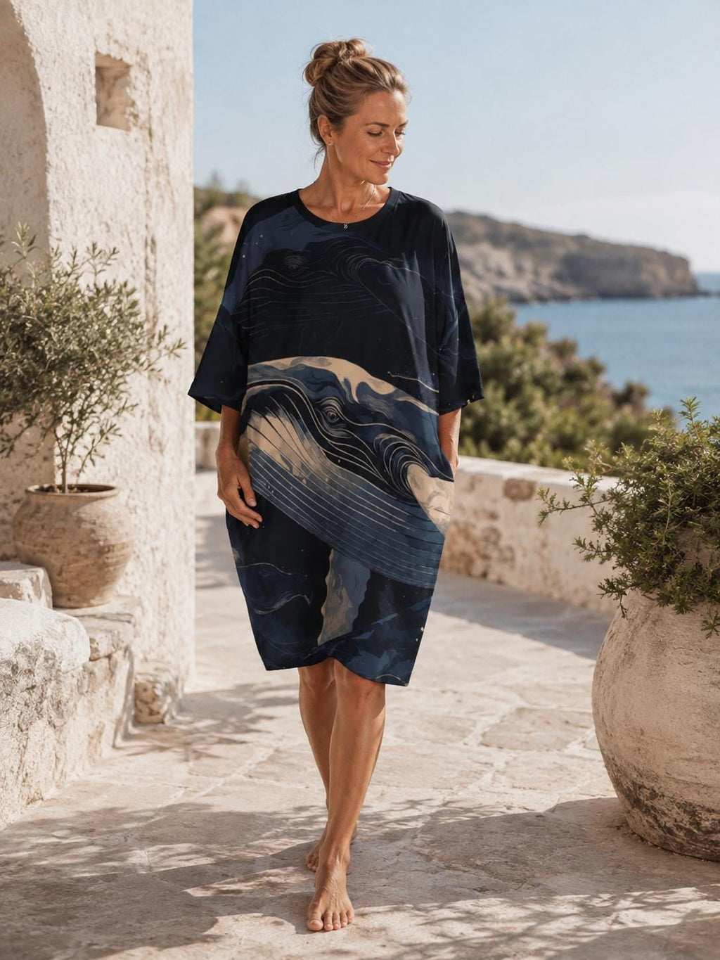 May include: A knee-length, loose-fitting dress featuring a dark navy blue base with a stylized, abstract graphic print of a whale in shades of light blue, cream, and white. The garment has a round neckline, short sleeves, and a relaxed, straight silhouette.