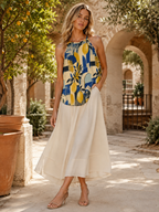 Mediterranean lemon print sleeveless top styled with an ivory skirt in a citrus courtyard